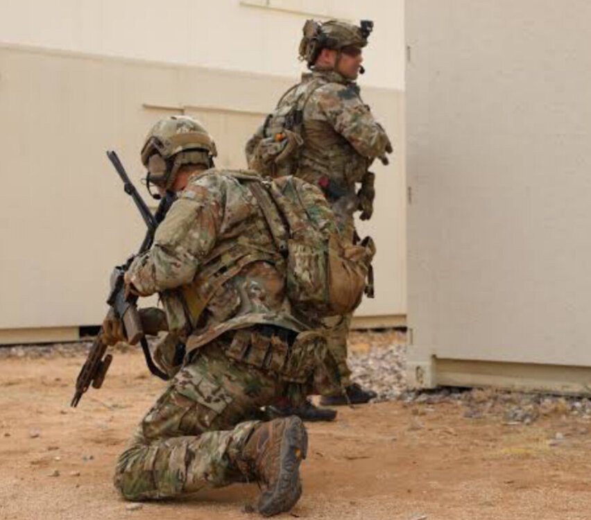 Could contain: soldier, military, army, camouflage, military camouflage, military person, infantry, military organization, weapon, troop, marines, squad, military officer, non-commissioned officer, organization, rifle, ballistic vest, gun, cargo pants, firearm, ranged weapon, clothing, military rank, helmet, airsoft, gun barrel, assault rifle, machine gun, combat, grenadier, government agency, ground, military uniform, wall, person, uniform, outdoor